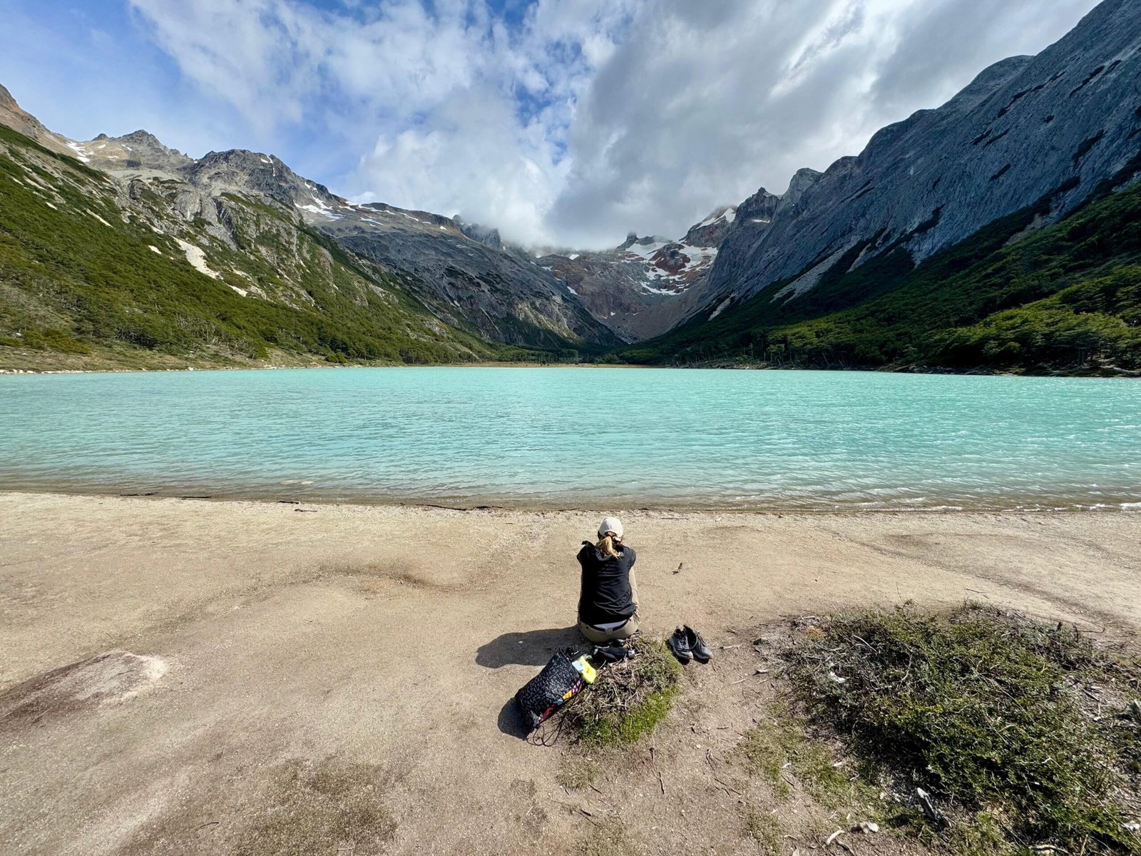 Persona sentada frente a la Laguna Esmeralda en Ushuaia, disfrutando de la tranquilidad y la vista panorámica sin turistas al llegar temprano con XPLOR TURISMO