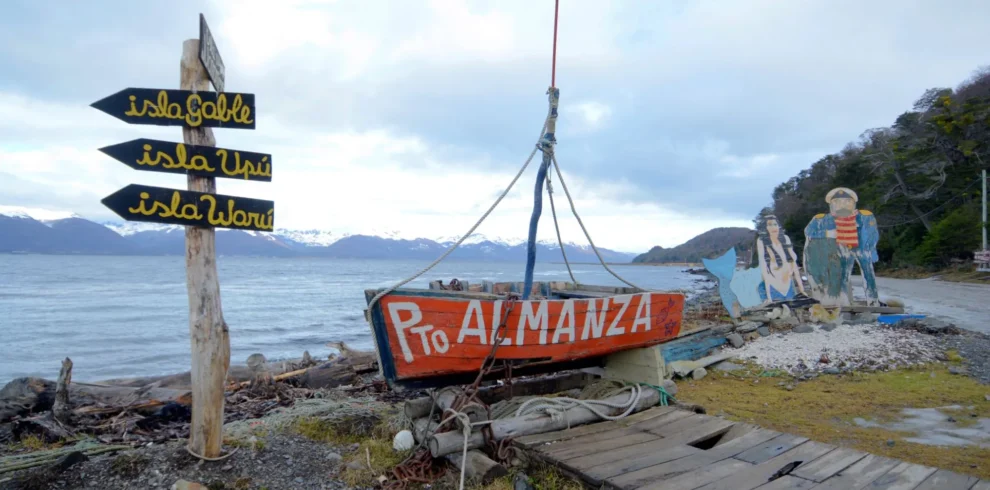 Cartel de bienvenida artesanal en Puerto Almanza con vista al Canal Beagle e islas cercanas.