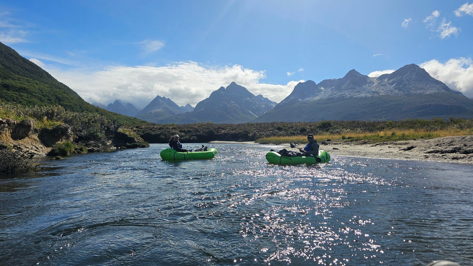 Personas practicando packrafting en el Río Olivia con montañas de los Andes Fueguinos al fondo en Ushuaia.